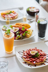 Fruits, smoothies and strawberry tartlet on restaurant table