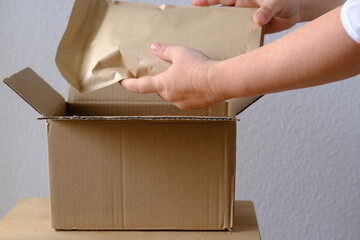 close-up of female hands take out package from open cardboard box of medium size postal box with...