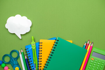 Collection different bright school stationery  and notebooks on green background, flat lay. Back to school concept.