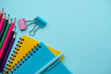 Collection different bright school stationery  and notebooks on blue background, flat lay. Back to school concept.
