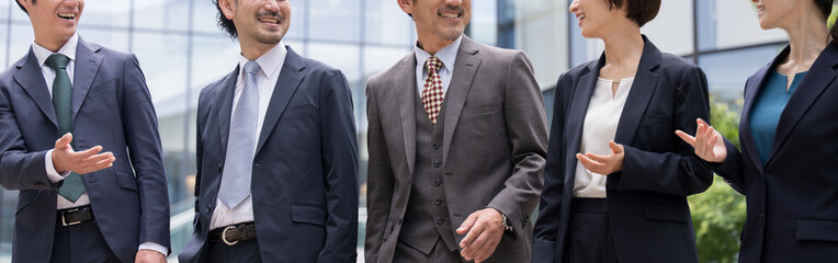 年齢や性別に幅や多様性のあるスーツを着たカッコいいビジネスマンチームが歩くイメージ(複数) 使いやすい口元のみの顔無しのバナー