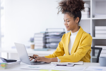 Young business african american woman office worker analyst sitting at desk working on laptop...