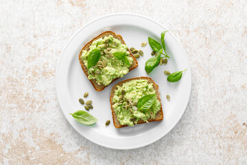 Avocado sandwich with pumpkin seeds. Healthy vegetarian avocado toast with rye bread for breakfast. Vegan menu. Top view - 604934860
