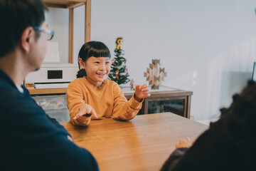 リビングで手話を使って会話をするろう者の父母とコーダの娘