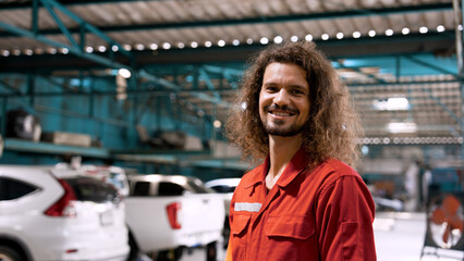 Caucasian mechanic who specializes in car repairs Standing in a large mechanic's red suit. Standing with a smile showing a good service mind in repairing cars for customers. impress customers