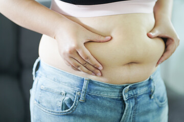 Naklejka premium Obese Woman with fat upset about her belly. Overweight woman touching his fat belly and want to lose weight. Fat woman with tight clothing worried about weight diet lifestyle concept