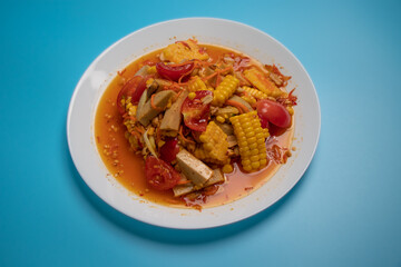 Corn Papaya Salad in white plate on blue background