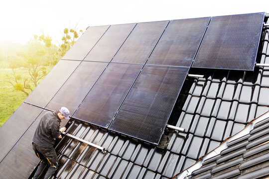 Technician installing solar panels on the roof of a house