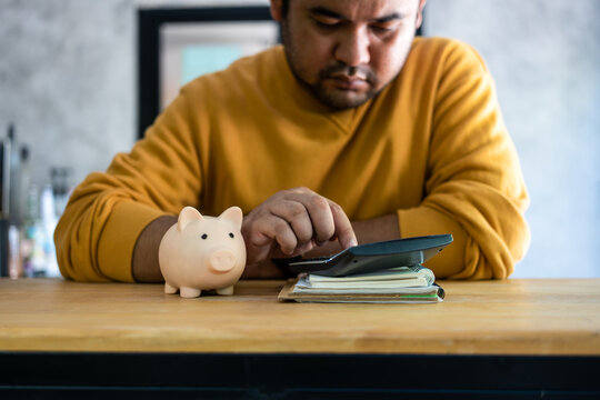 Focused serious young man calculating expenses and managing household family budget in living room. Debt and tax, expression and emotion concept.