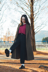 公園で秋を感じているコートを着た表皮水疱症の日本人女性