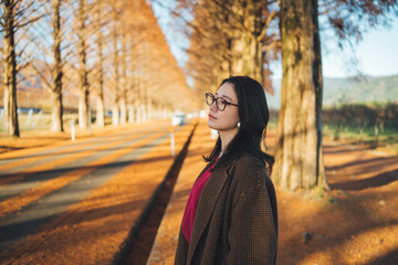 公園で秋を感じているコートを着た難病を持った日本人女性
