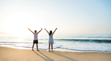 Young couple embracing enjoying ocean on beach.