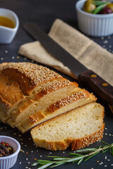 Sliced loaf of bread on a dark rustic table background. Close up. Copy space