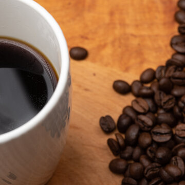 Black Coffee with Coffee Beans on the side on a Wood Board