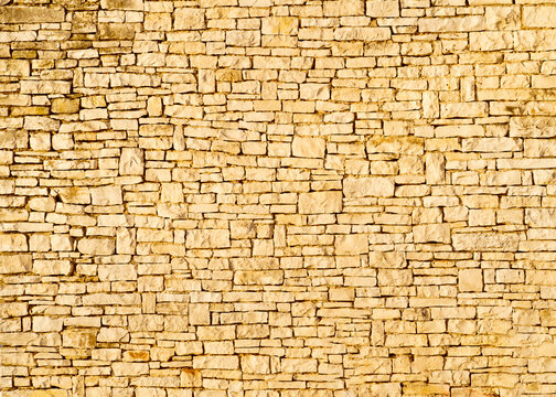 horizontal texture of an old wall made of rubble stone, brown sandstone and old plaster