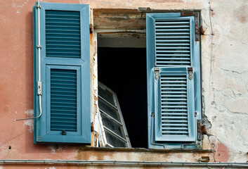 Close-up of the ruined window of an abandoned house with blue wood shutters, Genoa, Liguria, Italy