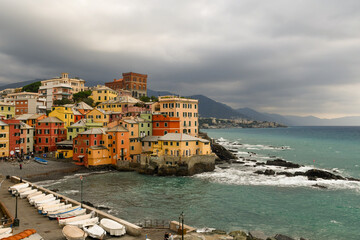 Fototapeta na wymiar Elevated view of the old fishing village with dry boats on the quay and the coastline with the Promontory of Portofino in the background in a cloudy autumn day, Boccadasse, Genoa, Liguria, Italy