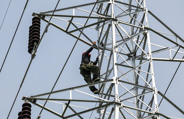 lineman climbing on electrical transmission line tower
