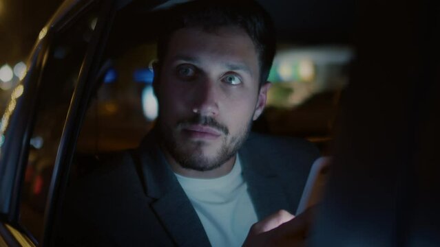 
Slow Motion of Handsome Businessman Using his Mobile Phone During Travel in Modern Car with Driver in City Center at night. Shot in 8K. Concept of Business, Success, Traveling, Driverless Transport