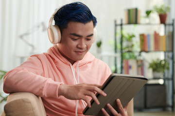 Smiling young man watching show on tablet computer