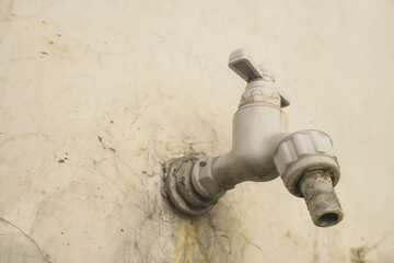 Old weathered white water faucet on the wall. Concept for save water, saving energy, no water,...