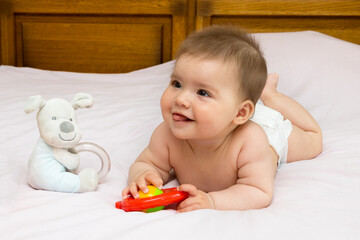 baby girl on mother's bed playing with a rattle