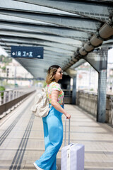 Happy tourist with backpack at the train station looking at his smart phone