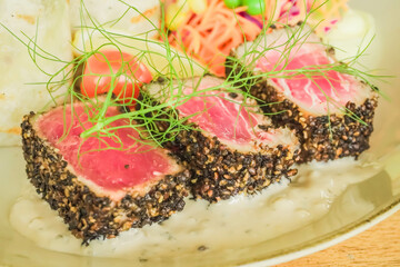 Three pieces of seared tuna with salad wrapped and quinoa on wooden table. Concept for healthy food, fat loss, weight loss, diet menu, vegetarian vegan, whole organic food, omega-3, dietary fiber.