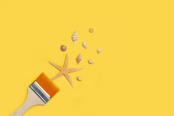 Pincel de pintura de con estrellas de mar, caracoles y conchas sobre un fondo amarillo brillante liso y aislado.  Vista superior y de cerca. Copy space