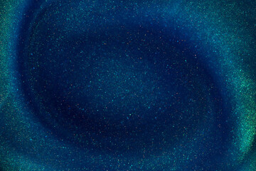 Gold Dust Particles Creating Spiral Waves in a Blue Liquid with a Green Tint. Abstract Glittering background. A whirlpool of shiny particles in a dark green thick fluidity.