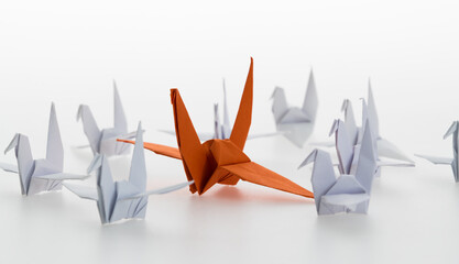 A orange origami crane stands out