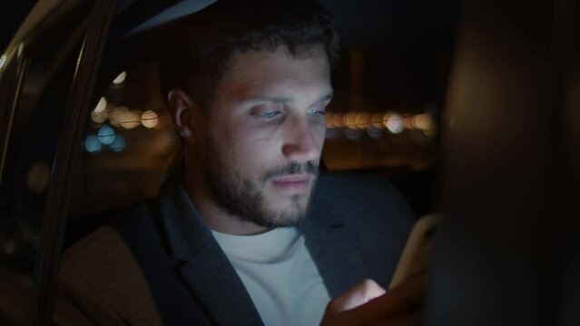 
Casual young man using smartphone in a car. He is checking mails, chats or the news online.
