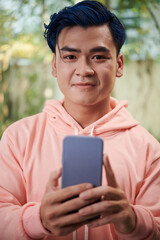 Fototapeta premium Portrait of joyful young man with blue hair taking selfie