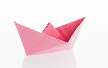 Pink origami boat on white background