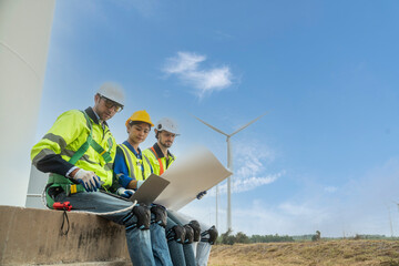 Team of female engineers and two foreman sit at the wind turbine station and talk holding blueprints   work to inspect and repair wind turbines to produce electricity at the wind turbine station.  © supAVADEE BUTRADEE