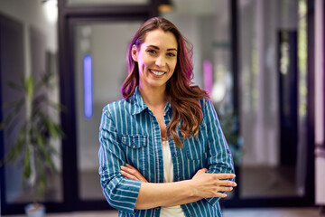Portrait of a smiling businesswoman with folded hands standing at the office.