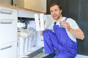 Plumber working change cartridge filter for water in kitchen. Concept filtration system.