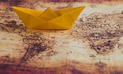 Yellow origami boat on world map background