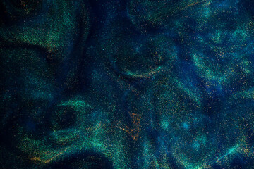 Bursting Gold Dust Particles in Blue Liquid. Abstract gold sparkling particles in blue fluid with green tints. Abstract fantasy background of shiny golden dust.