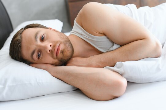 Bright shoot of upset man lies in the bed