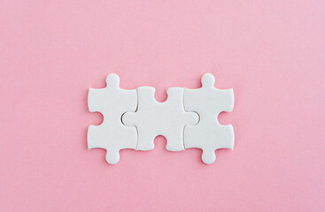 Three puzzle pieces on pink background