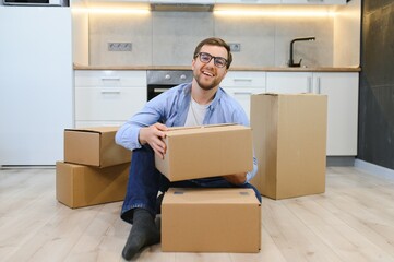 moving, people and real estate concept - happy smiling man with boxes at new home