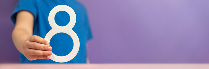 Number 8 in hand. A hand holds a white number eight on a purple background, eight percent per annum. The concept of international women's day on March 8. Advertising banner or greeting card.