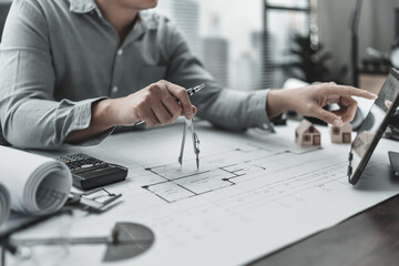 Architect using divider compass working on blueprint.  House planning design and construction concept.