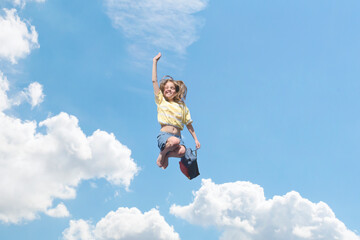 School vacation. A teenage girl with a school bag jumping in the sky. Start of school holidays