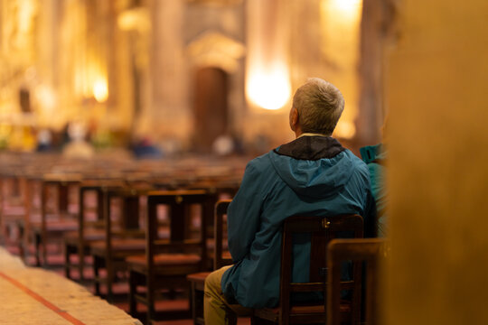 An elderly man sits at the entrance to the church and listens to a sermon