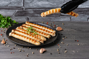 Fresh fried chicken sausages in a plate on a gray table. Empty copy space