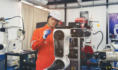 Male engineer worker repair automatic robotic arm. Male technician worker maintaining robot arm machine in workshop