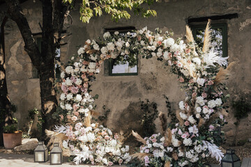 Wedding ceremony with round arch with floral arrangement in the fresh air at summer sunny day.	

