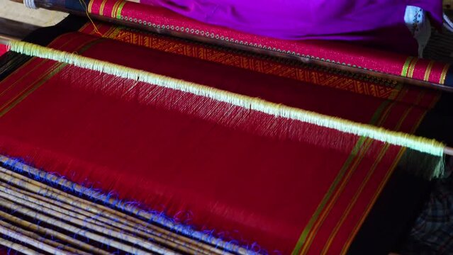 A hilly Chakma tribal woman weaves cloth with a hand-made loom in her own home in the Rangamati district.